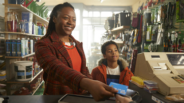 Photo of a woman paying with her debit card at a hardware store with her sun.